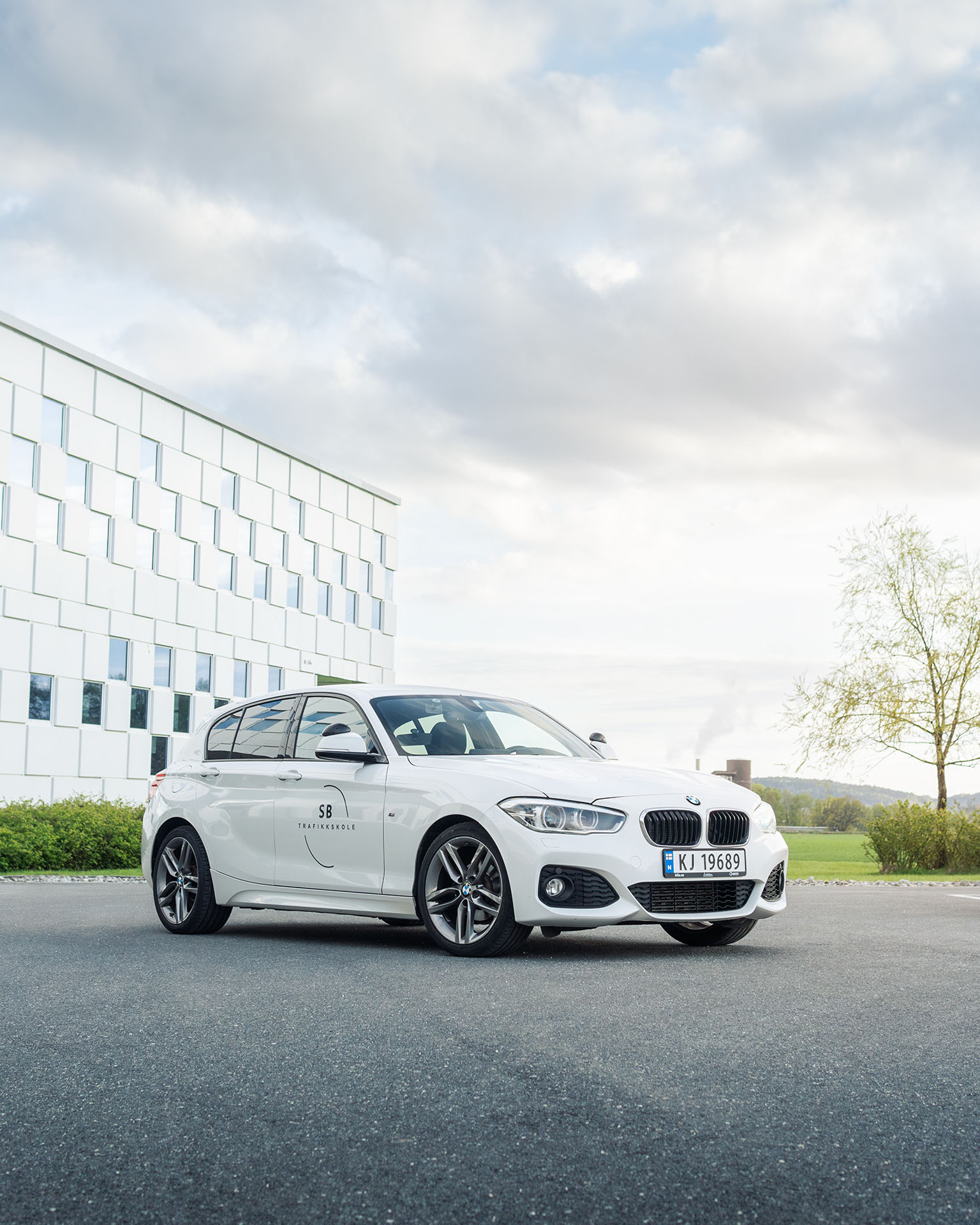 Bil til SB Trafikkskole i Sarpsborg, en hvit BMW. Står parkert utenfor Stjernebygget i Sarpsborg sentrum