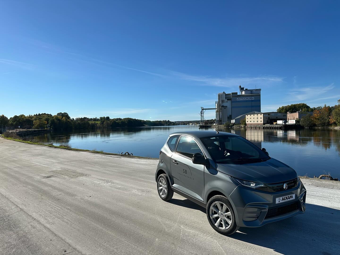 Biler til SB Trafikkskole i Sarpsborg, grå mopedbil står parkert utenfor ved vannet på Greåker