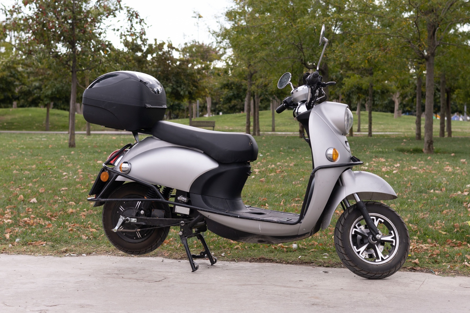 En moped / scooter, klasse AM146 står på støtte ute i en park